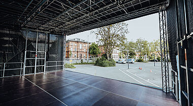 Eine Bühne mit Blick auf einen Parkplatz und Gebäude im Hintergrund.