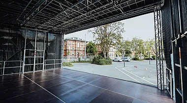 Eine Bühne mit Blick auf einen Parkplatz und Gebäude im Hintergrund.