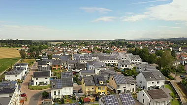 Satellitenaufnahme zeigt eine moderne Wohngegend mit Häusern und Solaranlagen auf den Dächern.