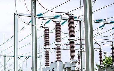 Techniker inspiziert Strommasten auf einem Feld.