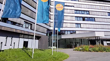 Modernes Bürogebäude der ENTEGA mit Fahnenmasten, Grünflächen und einem blauen Himmel.