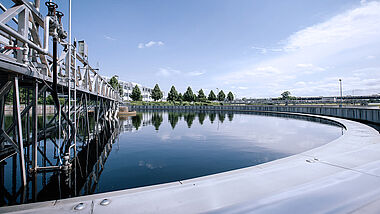 Klärbecken mit technischer Infrastruktur und umliegender Landschaft.
