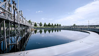 Klärbecken mit technischer Infrastruktur und umliegender Landschaft.