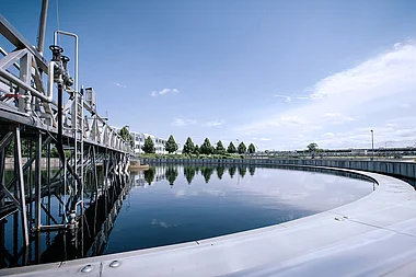 Klärbecken mit technischer Infrastruktur und umliegender Landschaft.