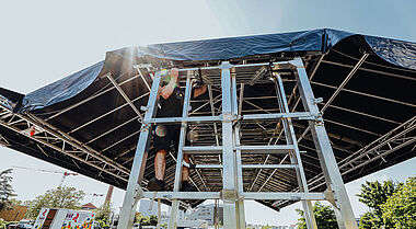 Bühnenaufbau mit Gerüst und Planen für ein Event im Freien.