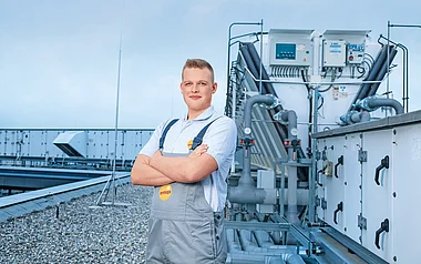 Ein Techniker inspiziert eine Klimaanlage auf einem Flachdach.