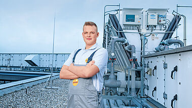 Ein Techniker inspiziert eine Klimaanlage auf einem Flachdach.