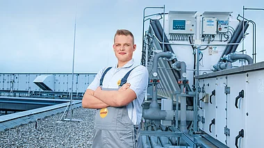 Ein Techniker inspiziert eine Klimaanlage auf einem Flachdach.