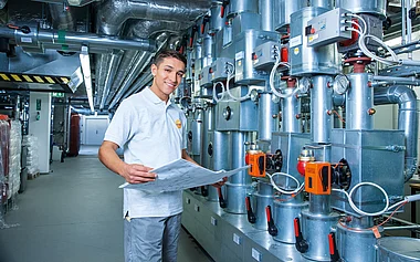 Techniker prüft Baupläne in einem technischen Anlagenraum.