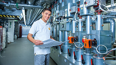 Techniker prüft Baupläne in einem technischen Anlagenraum.