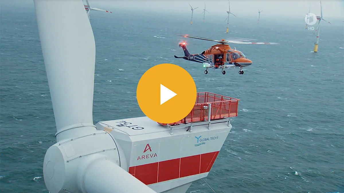 Windkraftanlage auf See mit einem Helikopter in der Nähe.