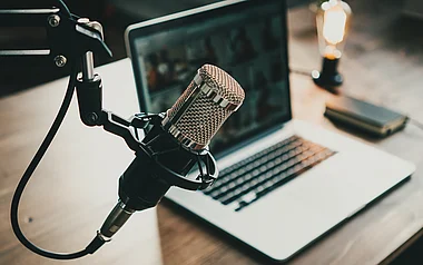 Ein Mikrofon steht vor einem Laptop, bereit für eine Aufnahme.