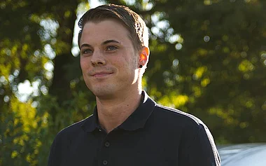 Mitarbeiter in Arbeitskleidung vor einem Firmenfahrzeug.