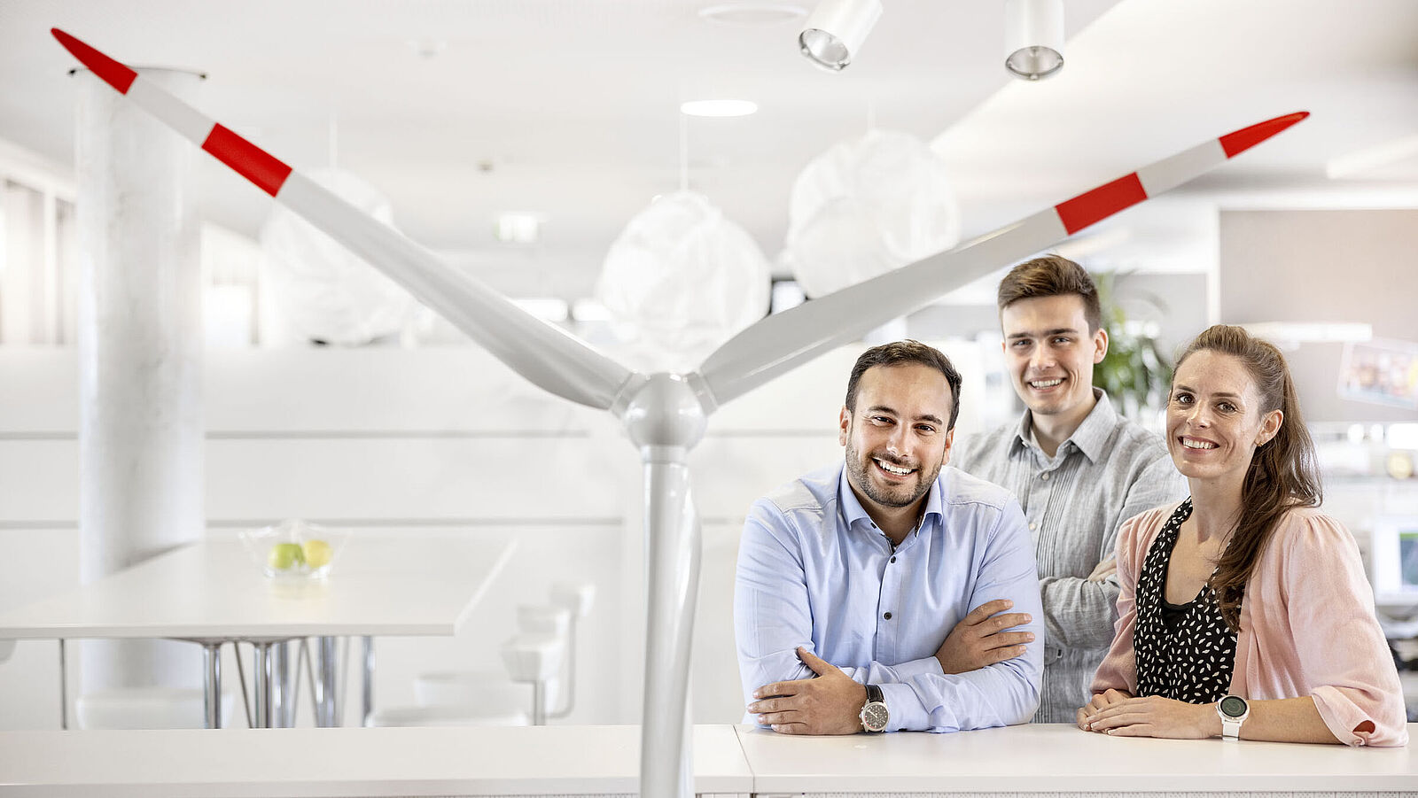 Drei lächelnde Fachleute posieren in einem modernen Büroambiente.