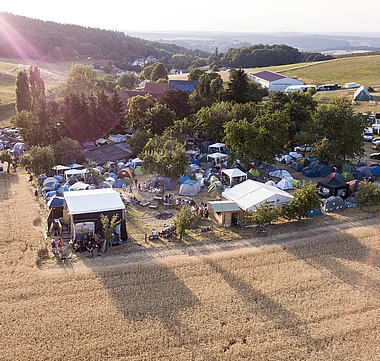 Übersichtliche Festivalplatzierung mit Zelten auf einer sanften Hügellandschaft.