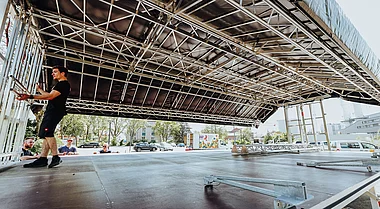 Techniker richten Bühnenaufbau mit Gerüst und Beleuchtungssystemen ein.