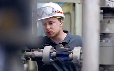 Techniker inspiziert eine Rohrleitung in einer Industrieanlage.