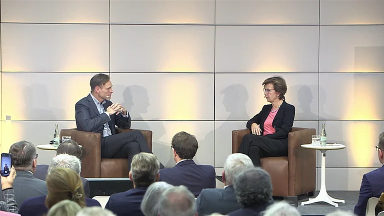 Zwei Redner sitzen im Gespräch vor einem Publikum.