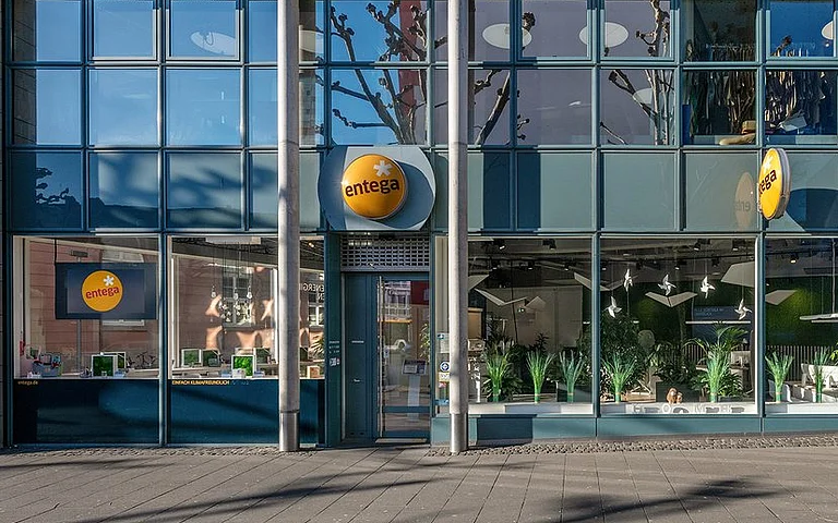 Moderne Büroräume mit Mitarbeitern und Pflanzen im Hintergrund.