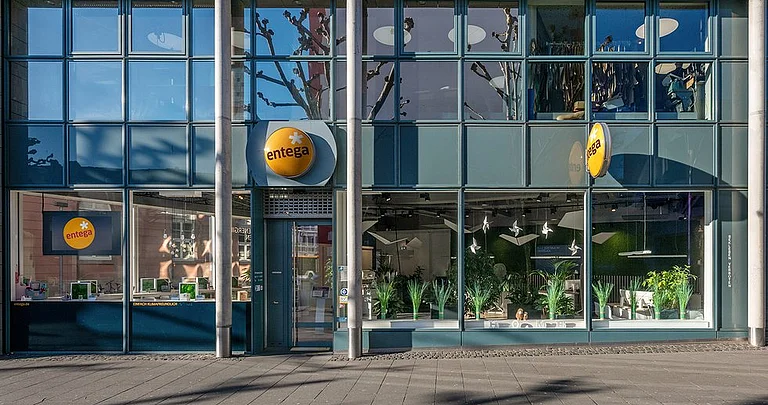 Moderne Büroräume mit Mitarbeitern und Pflanzen im Hintergrund.