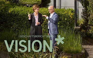 Zwei Fachleute diskutieren vor einem modernen Bürogebäude.