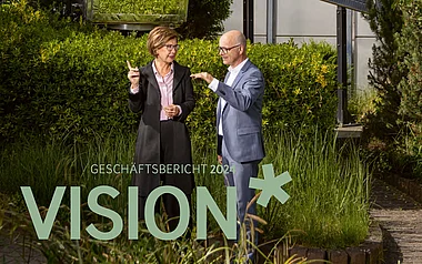 Zwei Fachleute diskutieren vor einem modernen Bürogebäude.