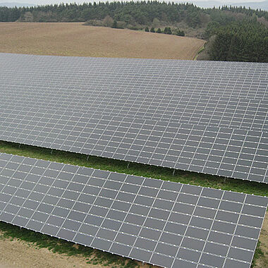 Solarmodule auf einem Feld, aufgenommen aus der Vogelperspektive.
