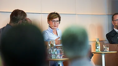 Eine Sprecherin präsentiert vor einer Gruppe von Zuhörern in einem Konferenzraum.