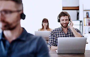 Mitarbeiter am Laptop führen ein Gespräch über Laptops in einem modernen Büro.