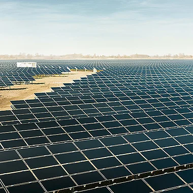 Solarmodule auf einer weitläufigen, sonnendurchfluteten Landschaftsfläche.