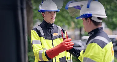 Techniker prüft elektrische Anlage mit Messgerät und Handschuhen.