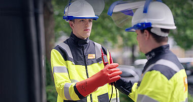 Techniker prüft elektrische Anlage mit Messgerät und Handschuhen.