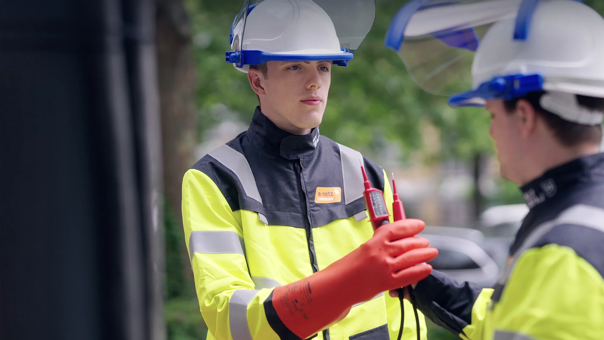 Techniker prüft elektrische Anlage mit Messgerät und Handschuhen.
