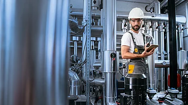 Techniker inspiziert mit Tablet in einer Industrieanlage.