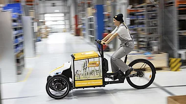 Fahrradkurier transportiert Pakete in einem Lager.