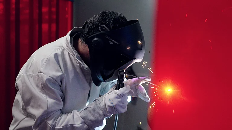 Schweißer führt eine Schweißnaht mit Schutzbrille und Handschuhen aus.