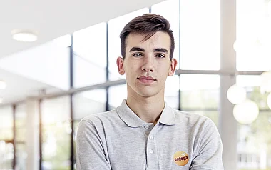 Mitarbeiter in Arbeitskleidung steht vor einer Glaswand.