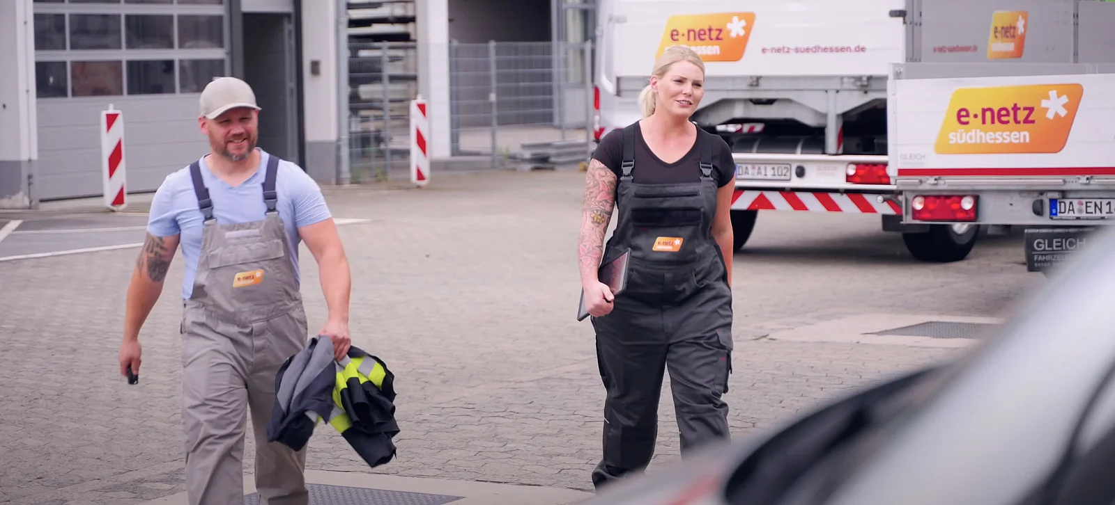 Techniker beladen ein Fahrzeug auf einem Firmengelände.