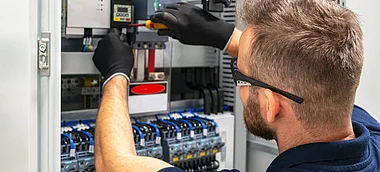 Techniker installiert eine Komponente in einem elektrischen Schaltschrank.