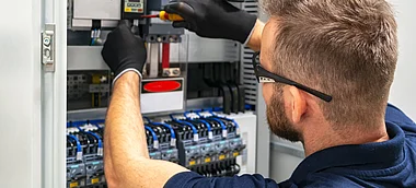 Techniker installiert eine Komponente in einem elektrischen Schaltschrank.