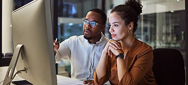 Zwei Fachleute diskutieren konzentriert vor einem Computerbildschirm.