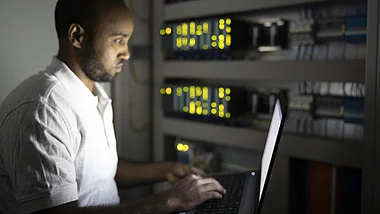 Techniker arbeitet konzentriert an einem Computer in einem Serverraum.