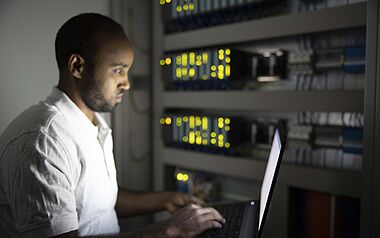 Techniker arbeitet konzentriert an einem Computer in einem Serverraum.