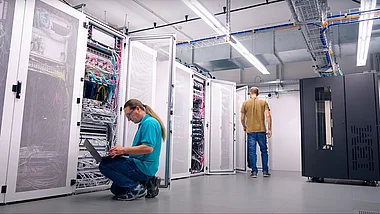 Techniker inspiziert Serverracks in einem modernen Rechenzentrum.