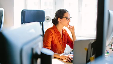 Eine Frau arbeitet konzentriert an ihrem Laptop im Zug.