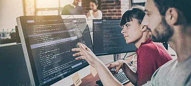 Zwei Entwickler arbeiten gemeinsam an einem Computerbildschirm.