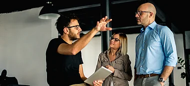 Ein Team diskutiert Ideen in einem modernen Büro mit Tablet.