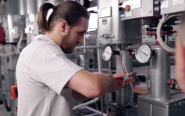 Techniker inspiziert eine Anlage mit Messinstrumenten und Ventilen.