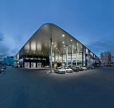 Moderne Autohausfassade bei Nacht mit mehreren Fahrzeugen vor der Präsentation.