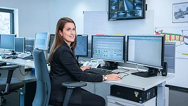 Mitarbeiterin überwacht technische Systeme in einem Kontrollraum.